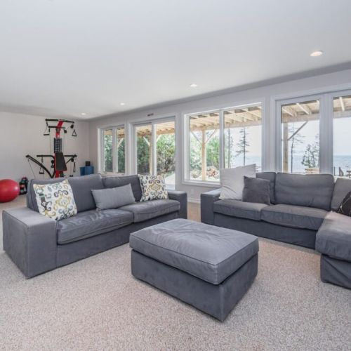 Lower level family room with workout space, pull-out couch, and a gorgeous view of the water.