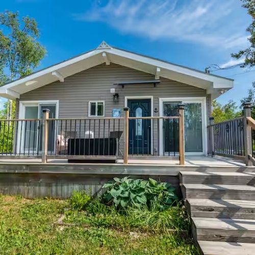 The front view of Sunset Cove — a cozy waterfront retreat with a wraparound porch, perfect for morning coffee or evening sunsets.