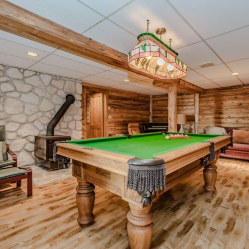 The ultimate entertainment space, this games room features a pool table, cozy seating, and rustic stone and wood finishes, making it the perfect spot for fun and relaxation.