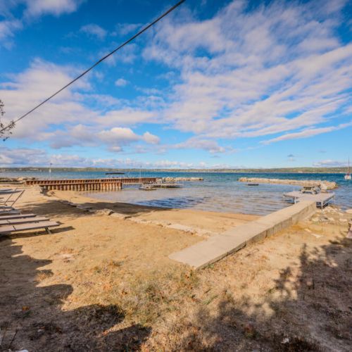Private beach area with a dock and lounge chairs by the water, providing a serene place to enjoy the lake and soak in the sun.