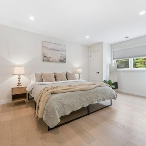 Peaceful and polished, this spacious bedroom features warm wood floors, soft neutral tones, and a king-size bed designed for total relaxation.
