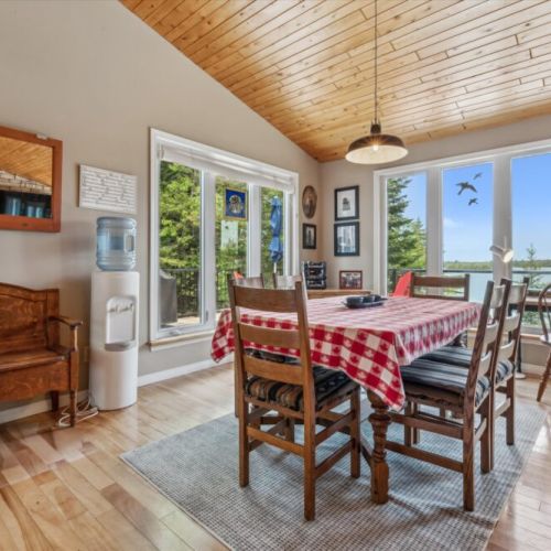 Bright and cozy dining area with large windows overlooking the trees and lake—perfect for family meals or board games with a view.