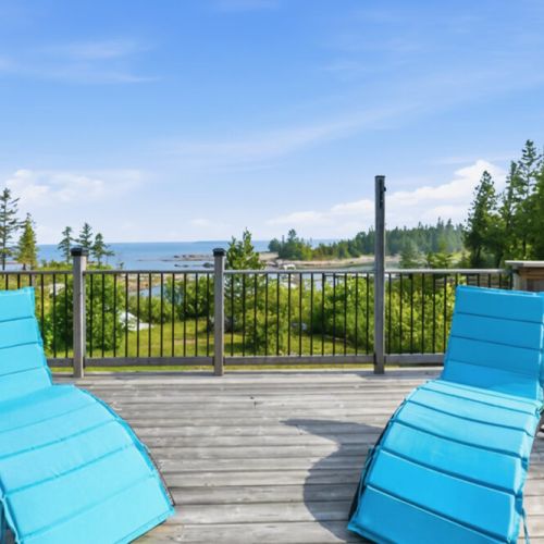 Comfortable loungers overlook the water and shoreline. A prime spot for sunbathing, reading, and enjoying a serene waterfront getaway.