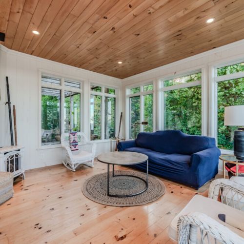 This sunroom offers a bright and serene space, with large windows providing natural light and views, complemented by cozy seating for scenic enjoyment.