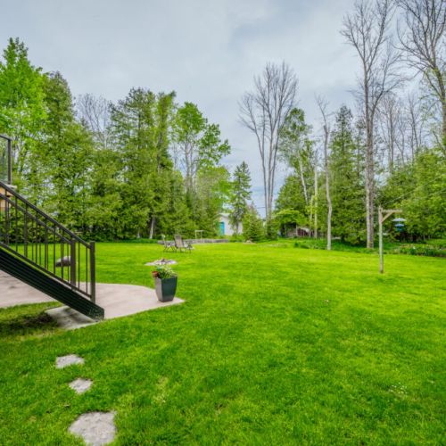 Expansive grassy backyard framed by mature trees, perfect for games, relaxation, or enjoying the quiet beauty of Georgian Bluffs.