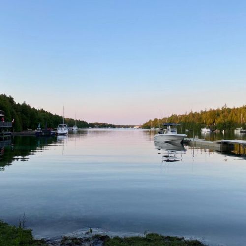 Wake up to the gentle charm of a quiet harbor, where the rising sun casts a golden hue on the treetops and the water lies still. A perfect moment to sip coffee on the dock and soak in the day’s peaceful beginning.
