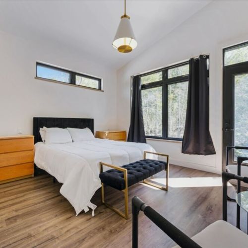 Bright and cozy primary bedroom with forest views and modern comfort.