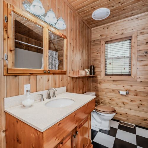 Rustic wood-lined bathroom with tub/shower combo—your personal spa retreat during your cottage rental stay.