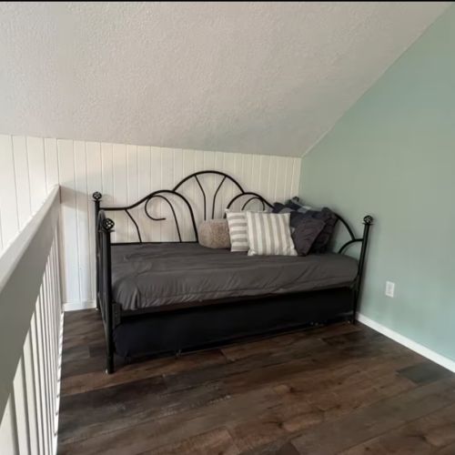 A cozy loft nook perfect for curling up with a book or accommodating extra guests — peaceful and private with a view of the trees.