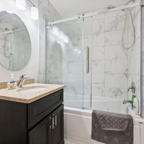 The bright main bathroom features modern finishes, a jacuzzi tub and shower combination, and plenty of space for guests.
