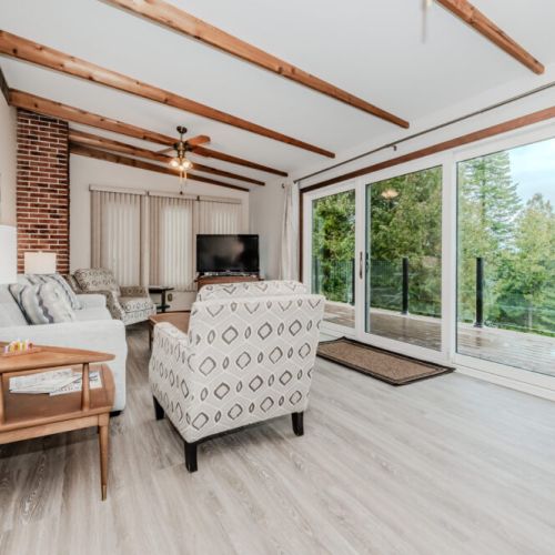 Relax in the bright and spacious main living room with vaulted ceilings, exposed beams, and incredible views of Colpoy’s Bay through massive glass doors.