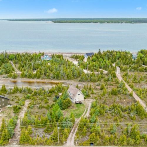 Aerial view of Dragonfly Cove and surrounding cottages, showcasing the quiet inlet and forested paths leading to Lake Huron’s rugged shoreline.
