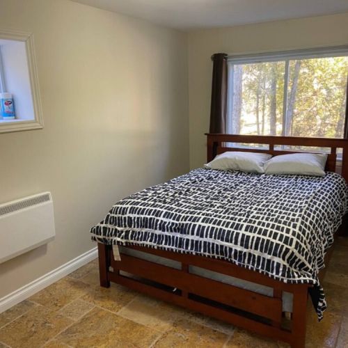 This serene bedroom offers forest views, a comfy queen bed, and stylish décor — an inviting haven for your travel adventures.