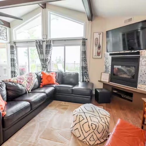 Relax in the inviting living room with plush seating, a fireplace, and floor-to-ceiling windows offering breathtaking lake views.