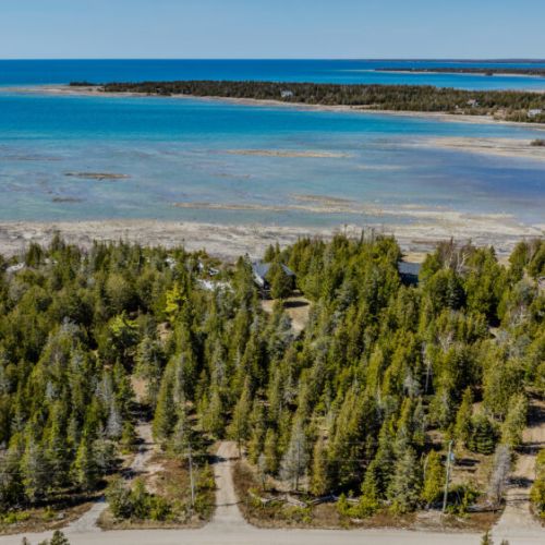 Breathtaking aerial view of the cottage nestled by the shoreline, offering endless forest trails and turquoise water adventures.