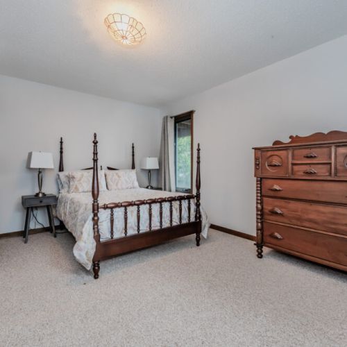 Spacious primary bedroom featuring charming wood furniture, ideal for a relaxing cottage stay by the lake.