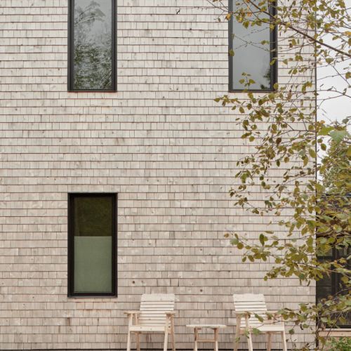 A quaint outdoor seating area with two Adirondack chairs on the porch, inviting guests to unwind and enjoy the surroundings.