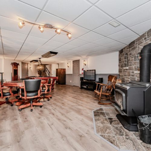 Spacious recreation room with wood stove, poker table, and lounge area—ideal for game nights, group fun, or cozy evenings during your vacation rental stay.