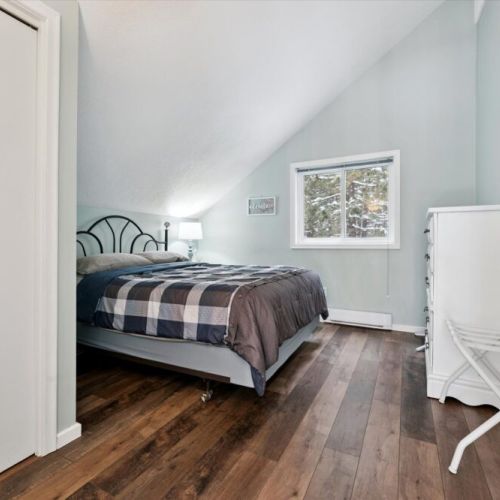 Charming bedroom with queen bed, vaulted ceiling, and serene woodland views