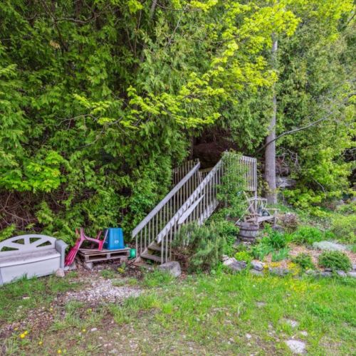 A charming forest staircase leads you deeper into nature, surrounded by vibrant perennials, shade-loving plants, and rustic decor. Nature truly begins at your doorstep.