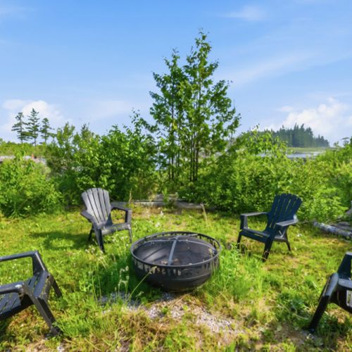 An outdoor fire pit surrounded by greenery and seating. Designed for evening gatherings, stargazing, and memorable cottage travel with family and friends.