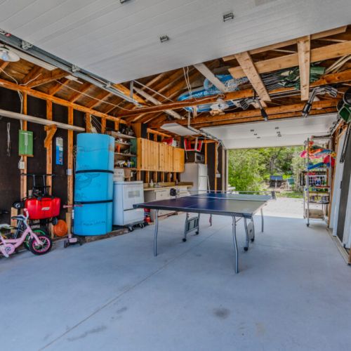 The spacious 'Boathouse' at Jack's Retreat doubles as a recreational area, featuring a ping pong table and ample storage for bikes, outdoor gear, and other items. The open layout and high ceilings make it a nice airy space during the summer heat.