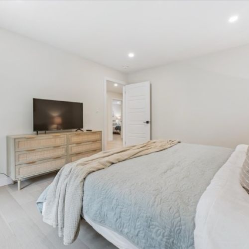 A tranquil retreat with soft textures and calming tones — this bedroom offers restful comfort with modern simplicity and a touch of entertainment.