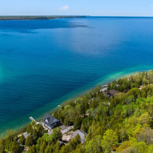 A coastal dream. Looking down at the perfect convergence of lush canopy, hidden docks, and the guardian lighthouse across the way.