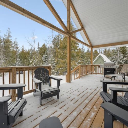 Spacious covered front deck with comfortable seating—perfect for outdoor meals, quiet mornings, and relaxing evenings surrounded by the woods.