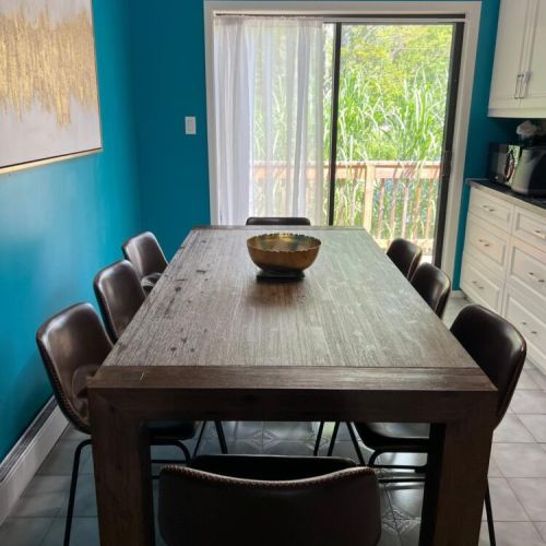 Gather around this spacious rustic table in our vibrant dining area, featuring stylish leather seating for eight. Enjoy meals bathed in natural light with a beautiful view of lush greenery just outside the sliding glass doors.