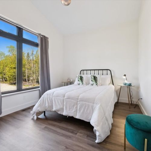 Peaceful guest bedroom filled with natural light and woodland views.