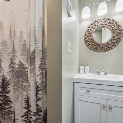 Stylish vanity with an intricately carved mirror and natural wood accents, offering a touch of rustic elegance in the main floor bathroom.