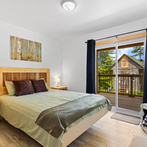 Unwind in this comfortable bedroom with private balcony access and peaceful forest views.