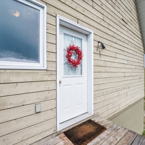 Step onto the inviting front deck and through the main door, where a vibrant wreath sets a cheerful tone.