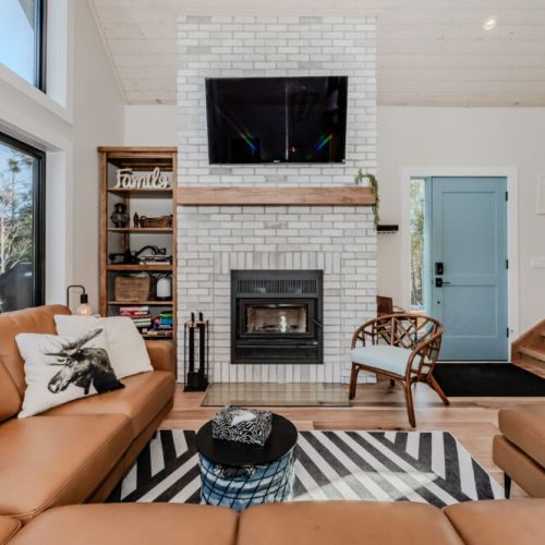 Gather around the brick fireplace in this beautifully designed great room with soaring windows, a large sectional sofa, and rustic charm—perfect for cozy nights in on your next countryside retreat.