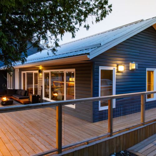 Enjoy the peaceful sounds of the waves as you relax on this spacious deck. The perfect spot to unwind and soak up the beauty of the lakefront. The warm lighting creates a cozy ambiance, perfect for relaxing by the firepit or enjoying the hot tub.