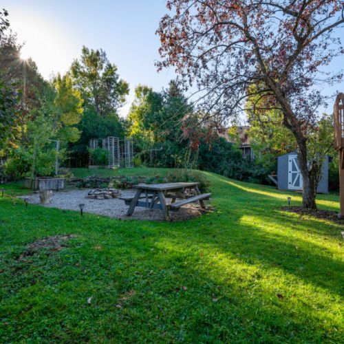 The expansive backyard is perfect for outdoor activities, featuring a picnic area, fire pit, and lush greenery.