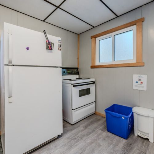 A compact kitchen space equipped with a fridge, stove, and recycling station, ensuring a practical and organized environment.