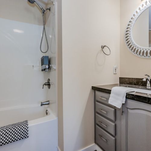 The clean and modern bathroom and shower area with fresh towels and a bright, colorful shower curtain ensures a refreshing experience.