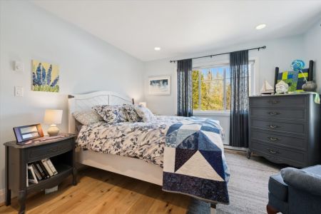 Rest comfortably in this bright and inviting bedroom, featuring a cozy queen bed and peaceful views of the surrounding trees.