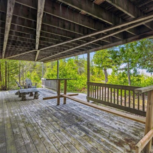 A peaceful nook for morning coffee or reading, this sheltered deck offers views of the wooded surroundings and access to the cottage’s scenic trails.