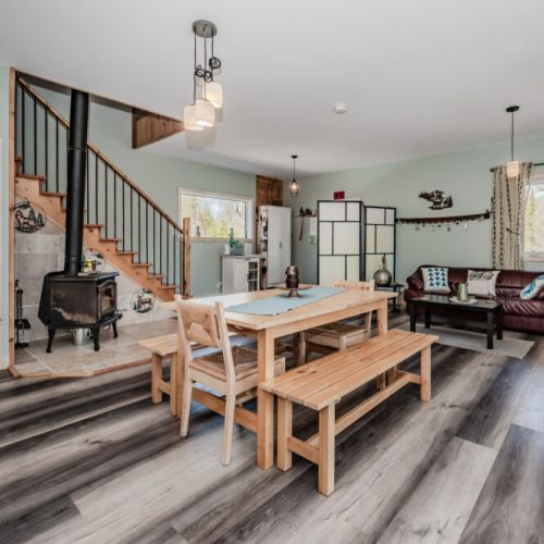 Open-concept comfort at its best—gather around the table, cozy by the woodstove, and enjoy seamless flow from kitchen to living space.