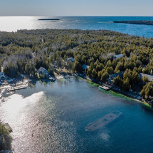 Big Tub Harbour: Stunning aerial view of a peaceful bay with shoreline cottages, surrounded by forest and open water—perfect for lakeside living and vacation rentals.