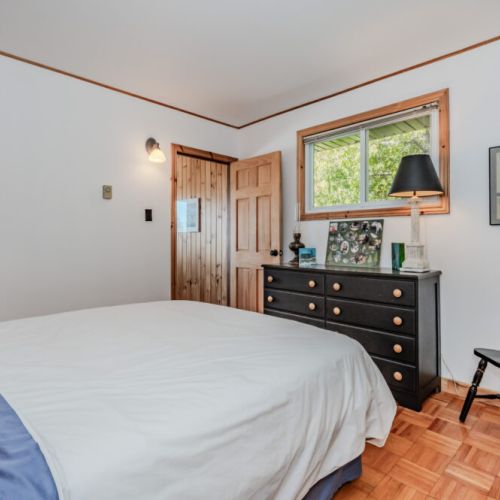 Bright and airy bedroom with peaceful forest views, cozy linens, and cottage charm — ideal for a restful vacation night’s sleep.