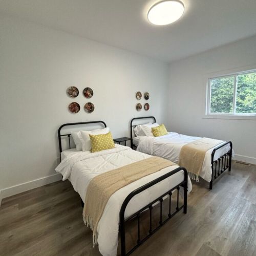This inviting twin bedroom features two comfortable beds, perfect for guests or children. The simple yet stylish decor, with cozy blankets and accent pillows, creates a warm and welcoming atmosphere.