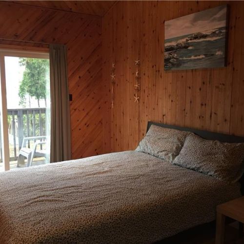 Bedroom 1: Comfortable bedroom with direct walkout to the deck—enjoy fresh air and peaceful lake views.