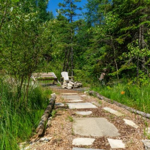 Charming stone path through the woods leads you deeper into nature and straight to your secluded backyard fire zone.