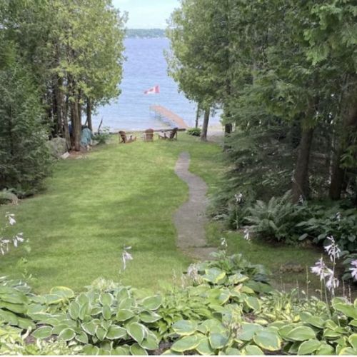 The sprawling backyard leads to the lapping shores of the bay, a peaceful place to embrace nature that is surrounded with trees for privacy.