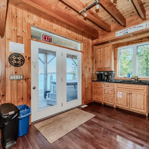 Rustic kitchen with direct deck access and views of the lake and hot tub—ideal for relaxed mornings, lakeside meals, and sunset dips.