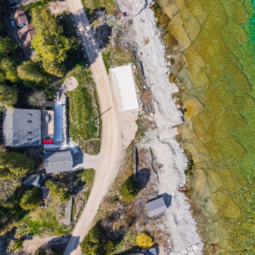 This stunning aerial view captures the property’s prime location, nestled right by the crystal-clear waters of the lake. It beautifully showcases the surrounding greenery and the pristine shoreline.